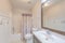 Small windowless bathroom interior with half-paneled wall and floral shower curtain