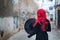 A small witch in a black dress with red hair on the street of the old city