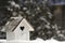 Small wooden birdhouse in snow against Christmas t