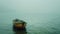 Small wooden boat sits alone on calm water, small wooden boat sits on foggy lake