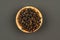 A small wooden bowl filled with cubeb pepper