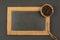 A small wooden bowl filled with cubeb pepper on an old black slate board