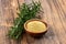 A small wooden bowl with ground rosemary and fresh rosemary twigs