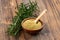 A small wooden bowl with ground rosemary and a small spice shovel and fresh rosemary twigs