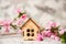 Small wooden cabin close-up and copy space. Miniature house, flowering branch in the spring. The concept of rush, purchase, exchan