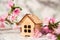 Small wooden cabin close-up and copy space. Miniature house, flowering branch in the spring. The concept of rush, purchase, exchan