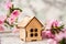 Small wooden cabin close-up and copy space. Miniature house, flowering branch in the spring. The concept of rush, purchase, exchan