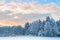 Small wooden chapel in snowbound frosty forest under sunrise sky