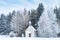 Small wooden chapel on snowbound frosty glade in snowy frozen forest