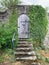 Small wooden door, entrance with an old stone staircase with an old wall, overgrown with ivy, a blank for the designer, wallpaper