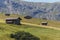 Small wooden farm house, cottage or log cabins on meadow on Alpe di Siusi, Seiser Alm, South Tyrol, Italy