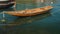 A small wooden fishing boat rocks on waves near the shore