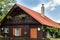 Small wooden house with red roof, white windows and geraniums