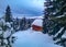 Small wooden lodge or cabana covered in snow, surrounded by icy evergreens overlooking the Carpathian Mountains, winter landscape