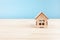 Small wooden model house on wood table. Mini residential craft house on blue background. Close-up view of small house model on