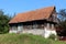 Small wooden old family house with dilapidated boards and broken roof with missing roof tiles on top of small hill