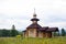 Small wooden orthodox temple. Made from thick logs. Brown roof, cross on the dome