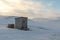 Small wooden outhouse hut in the middle of arctic landscape in winter