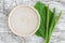 Small wooden plate as place for text, fresh greater plantain psyllium leaves and spikes flowers on white shabby wooden backgroun