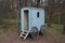 Small wooden trailer for transporting horses stands among the pine trees in autumn