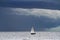 Small yacht on big ocean and dark clouds