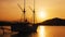 Small yacht moored near the shore on sunset, sun setting behind hill