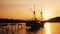 Small yacht moored near the shore on sunset, sun setting behind hill