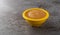A small yellow bowl filled with applesauce on a gray background