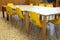 Small yellow chairs and tables inside a school classroom of the