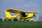 Small yellow charter airplane waiting on a green field to take off