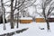 a small yellow cottage with a snow covered driveway in the foreground