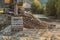 Small yellow excavator at pile of rocks and stones next to river, detail on digger bucket on ground. Construction at riverside