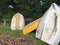 Small yellow metal boats or dinghies leaning against wooden fence