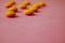 Small yellow orange beautiful medical pharmaceptic round pills, vitamins, drugs, antibiotics on a pink purple background, texture.