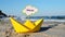 Small yellow paper boat with stick with the word RELAX stands on sandy beach