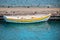 Small yellow rowboat tied to the dock with reflections in the water