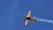 Small yellow stunt plane flies at 90 degrees releasing white smoke in slowmo