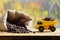 A small yellow toy truck is loaded with brown coffee beans around a full bag of grains. A car on a wooden surface against a backg