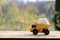 A small yellow toy truck is loaded with white sugar cubes. A car on a wooden surface against a background of autumn forest. Extra