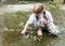 Small young girl writing simple words on concrete with white chalk. Child drawing with chalk on the ground outdoors. Art therapy