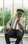 Smart african man in airline sitting, wearing pilot hat and looking to camera in meeting room with copy space. Business meeting