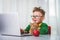 Smart and attractive little boy looking at the laptop, video call with someone. Family enjoy distant talk by video call