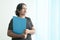 Smart and beautiful Indian corporate woman with a blue file standing by the office windows