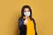 Smart black woman in medical mask showing thumb up on yellow background