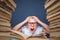 Smart boy in glasses getting crazy of reading book while sitting between two piles of books