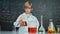 Smart boy inspect mixed liquid in laboratory beakers while holding. Erudition.