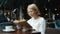 Smart business lady mature blonde reading book at table in restaurant relaxing