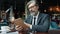 Smart businessman mature bearded man reading book sitting in cafe alone