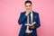 Smart casual man holding a book on pink background