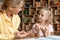 Smart caucasian girl preschooler learing to count with her mother helping, sitting at desk in living room and studying